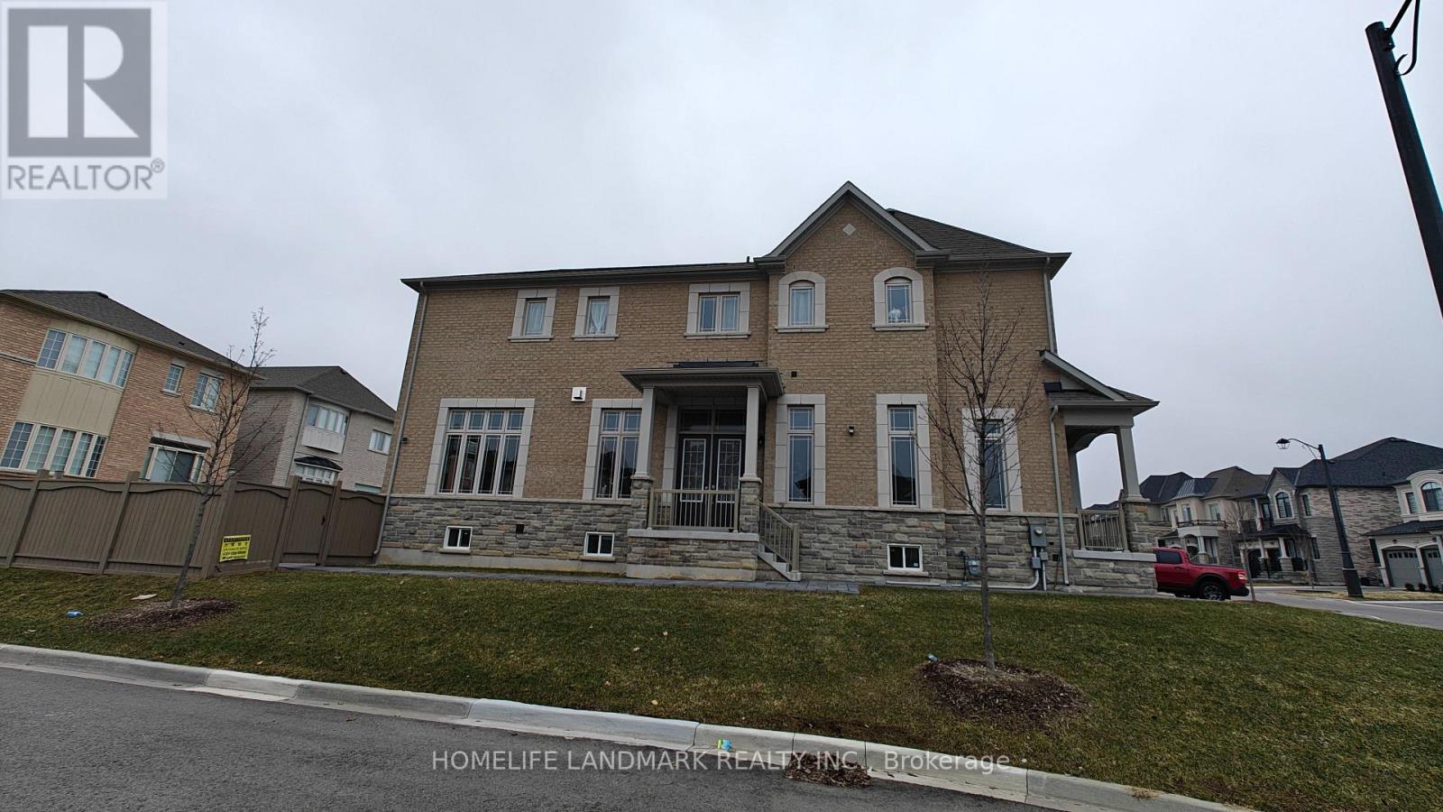 A large two-story house with a stone facade and a red car parked in front.