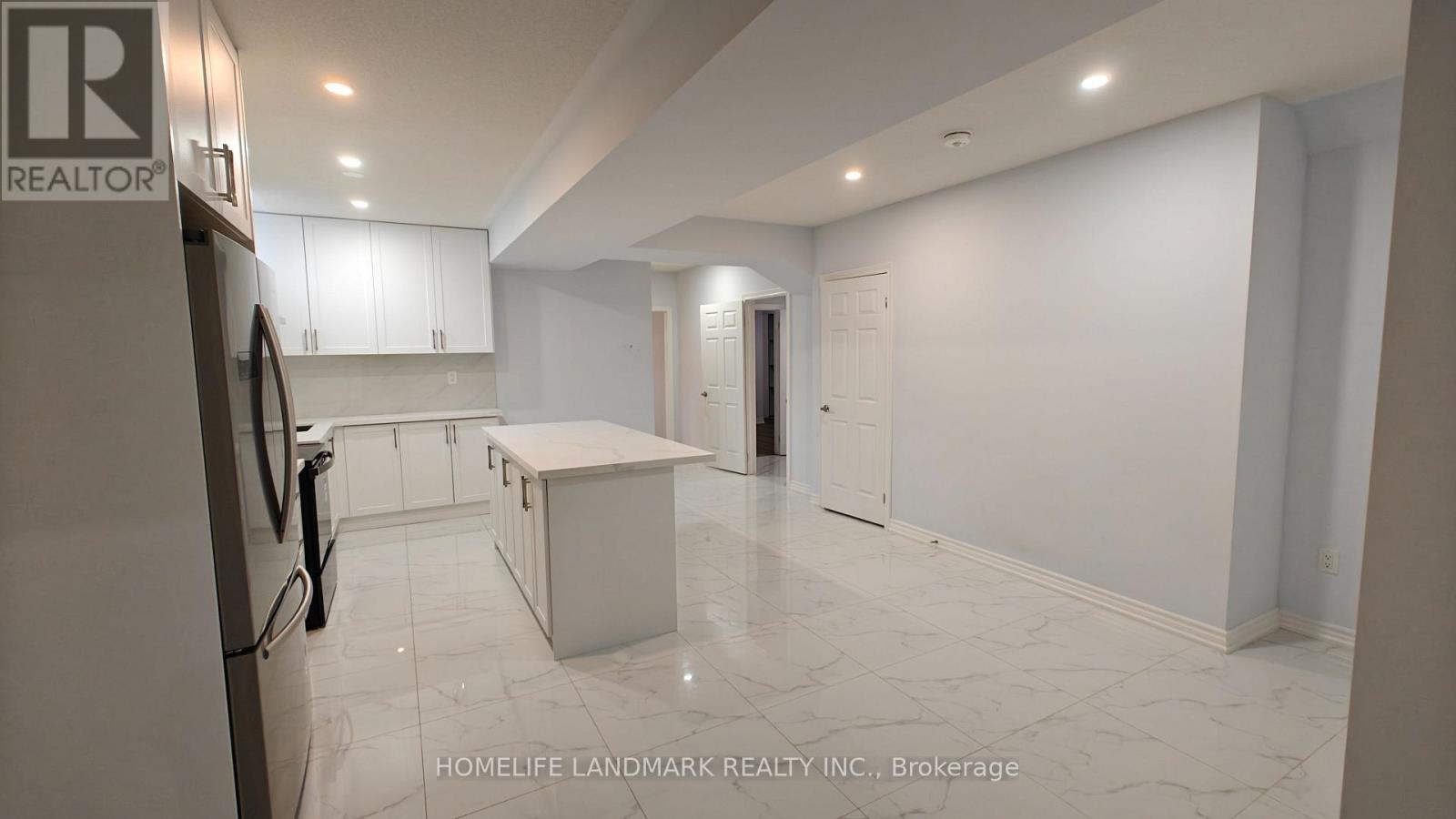 A kitchen with white cabinets and a marble floor.