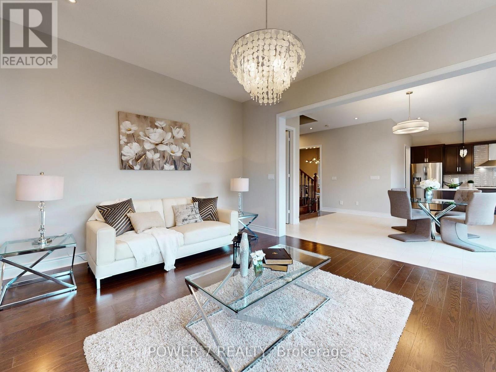 A living room with a glass coffee table and a chandelier.