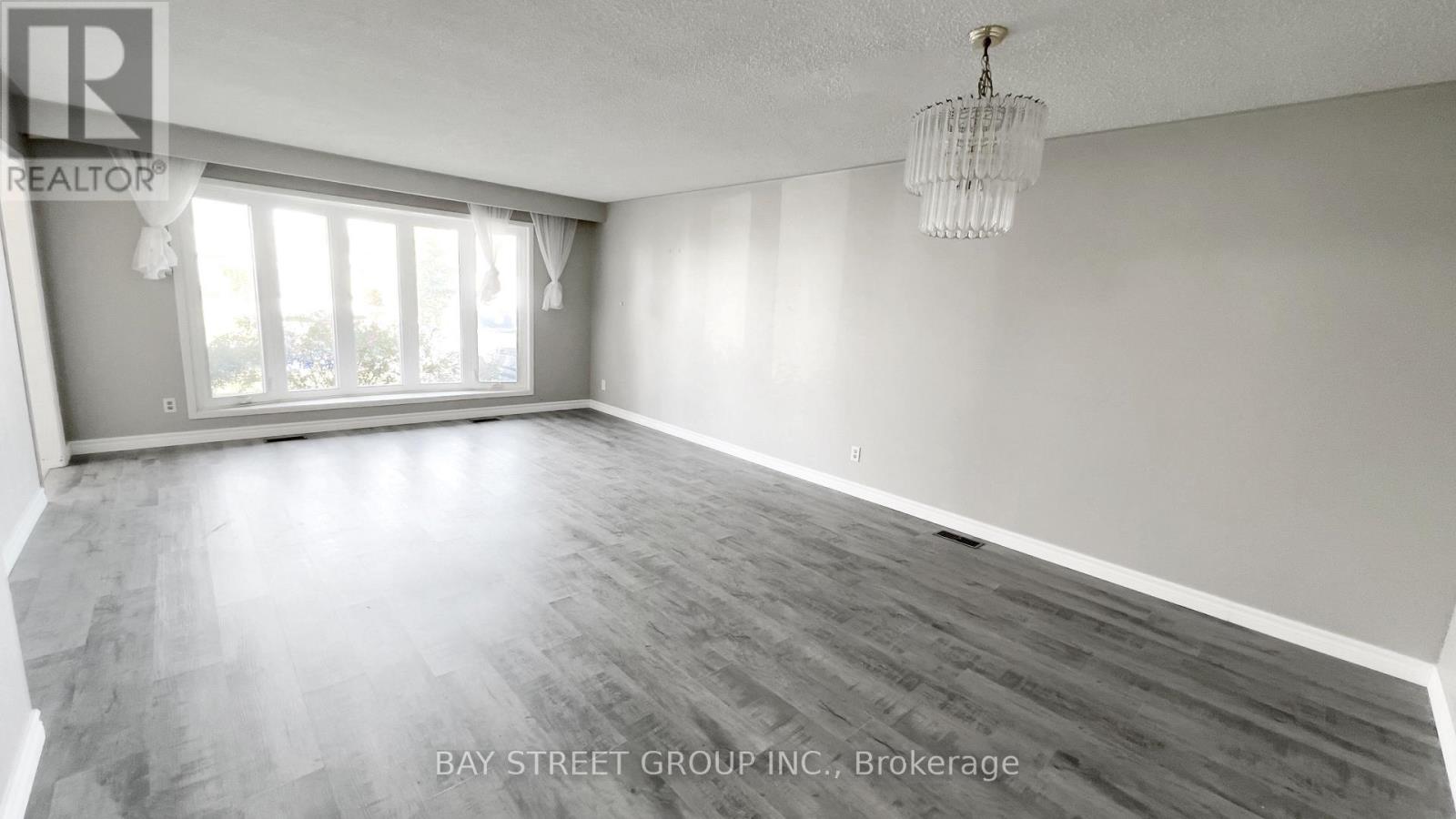 A spacious room with wooden flooring and a large window.