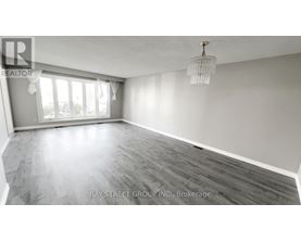 A spacious room with wooden flooring and a large window.