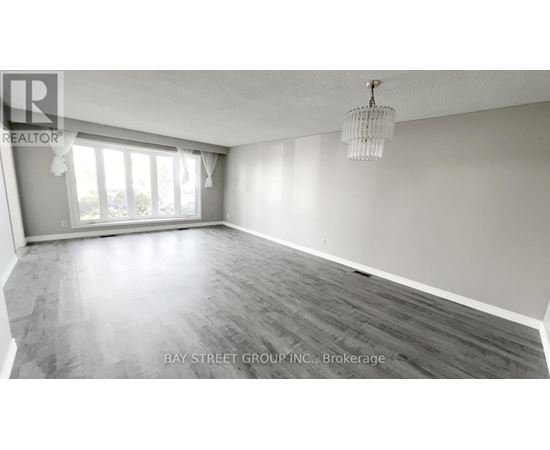 A spacious room with wooden flooring and a large window.