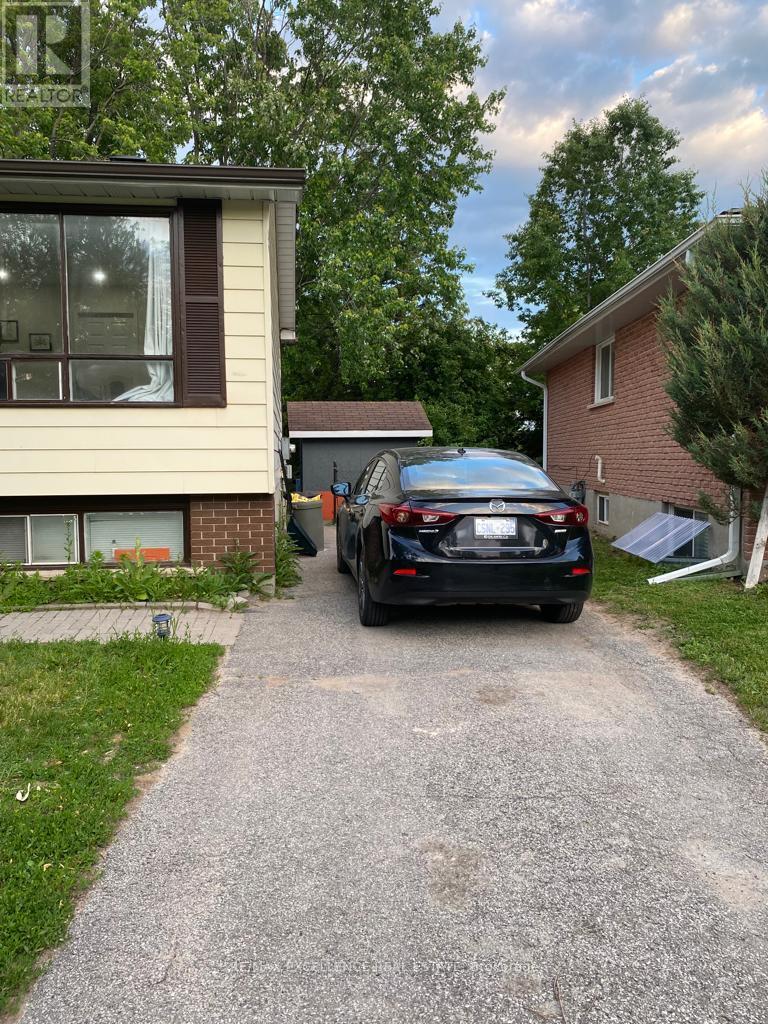 A black car is parked on a driveway in front of a house.