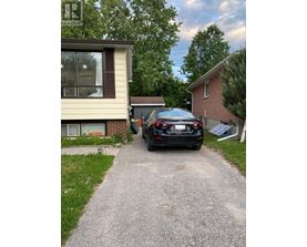 A black car is parked on a driveway in front of a house.