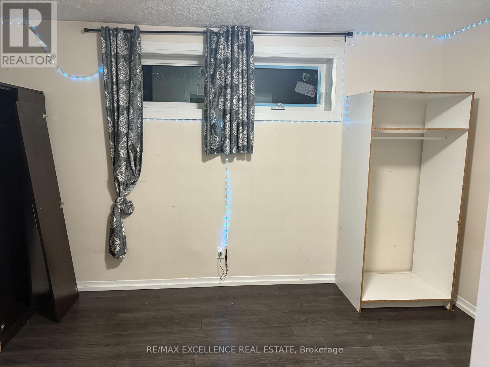 A room with a window, curtains, and a wooden floor.