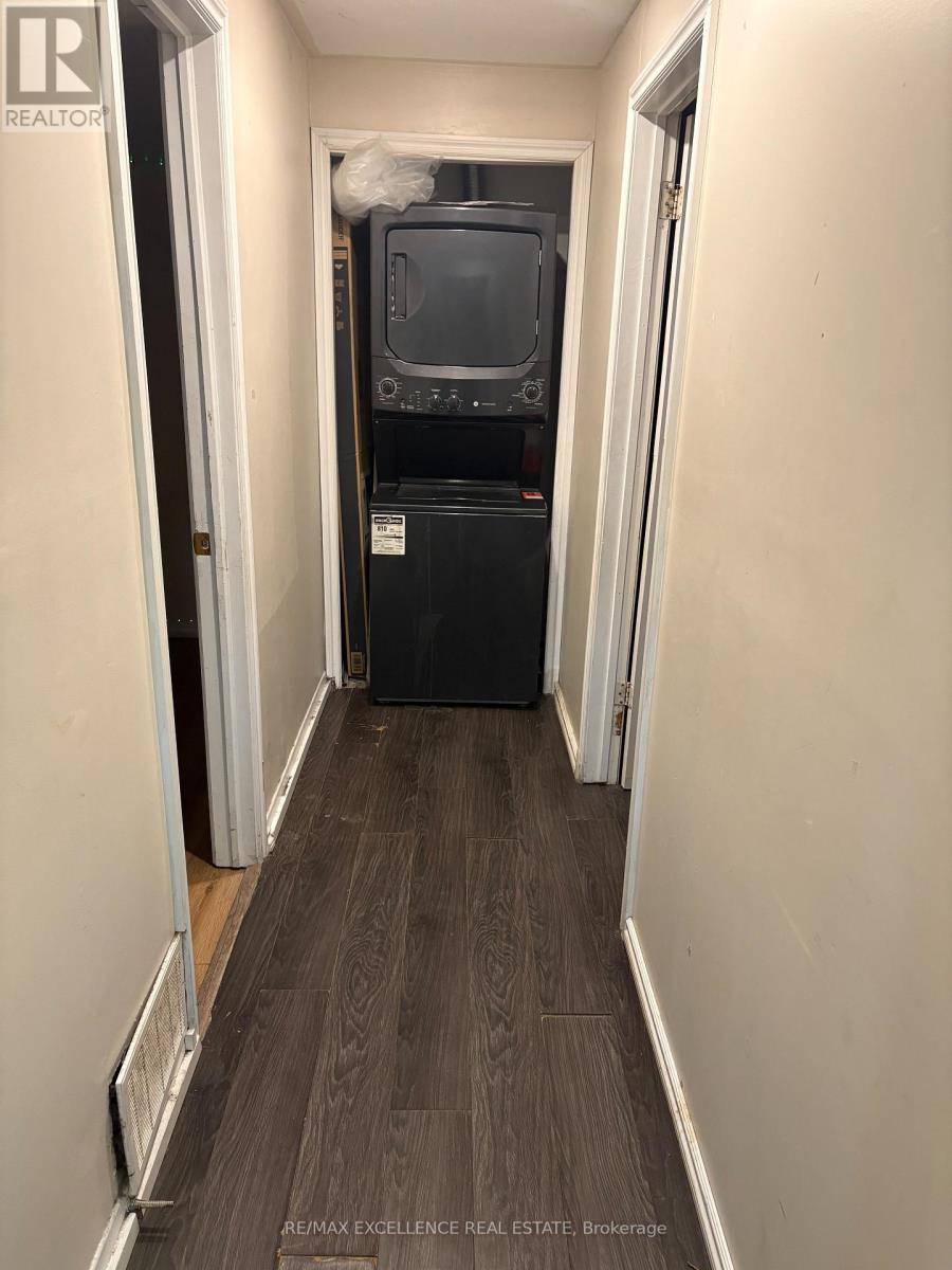 A long, narrow hallway with a black fridge and a TV on top of it.