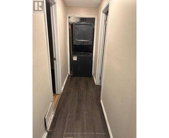 A long, narrow hallway with a black fridge and a TV on top of it.
