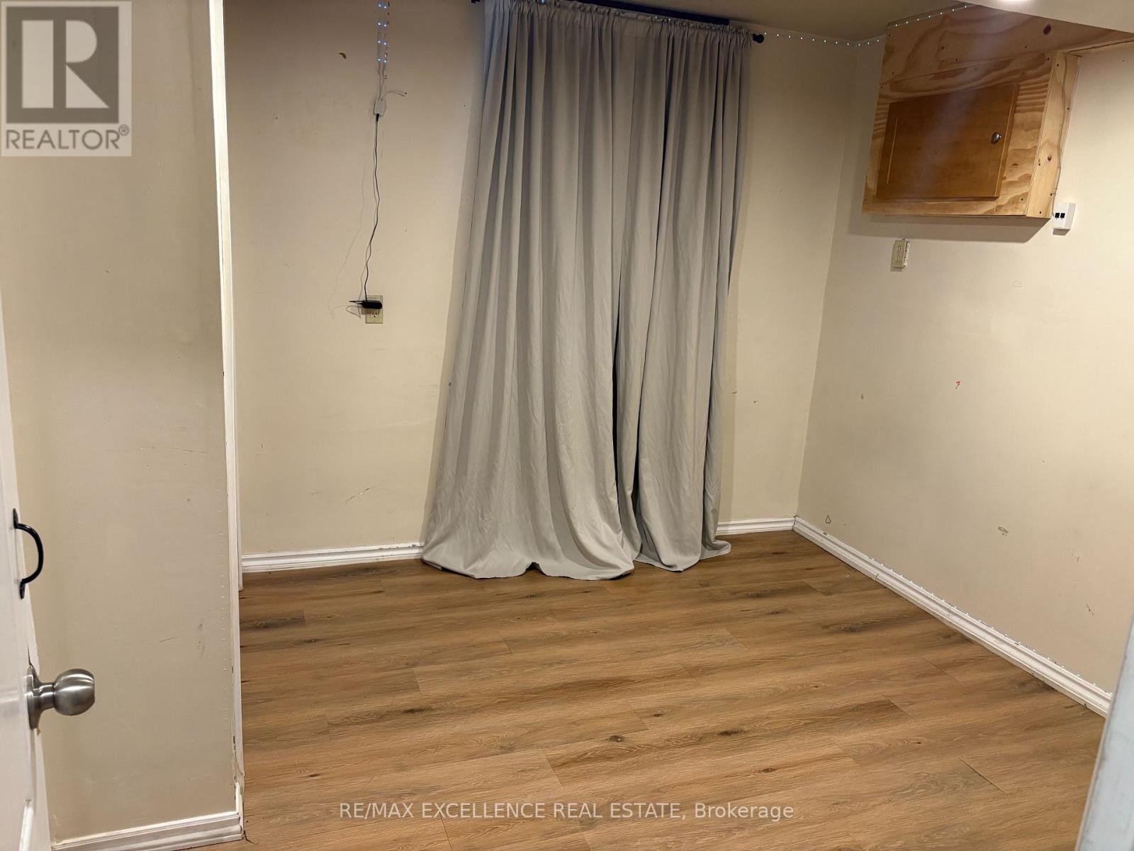 A room with a curtain and a wooden board on the wall.