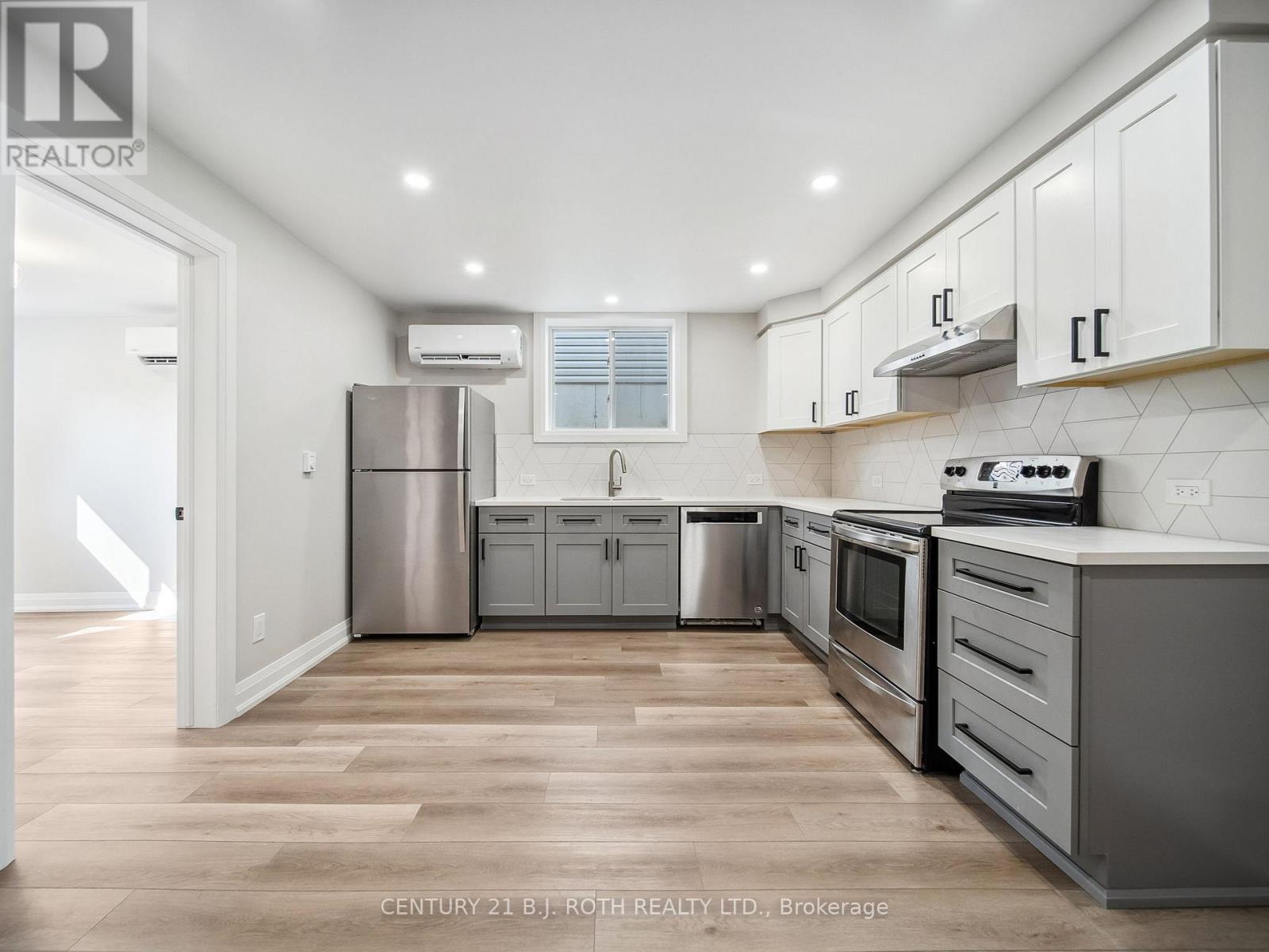 A modern kitchen with wooden floors and stainless steel appliances.