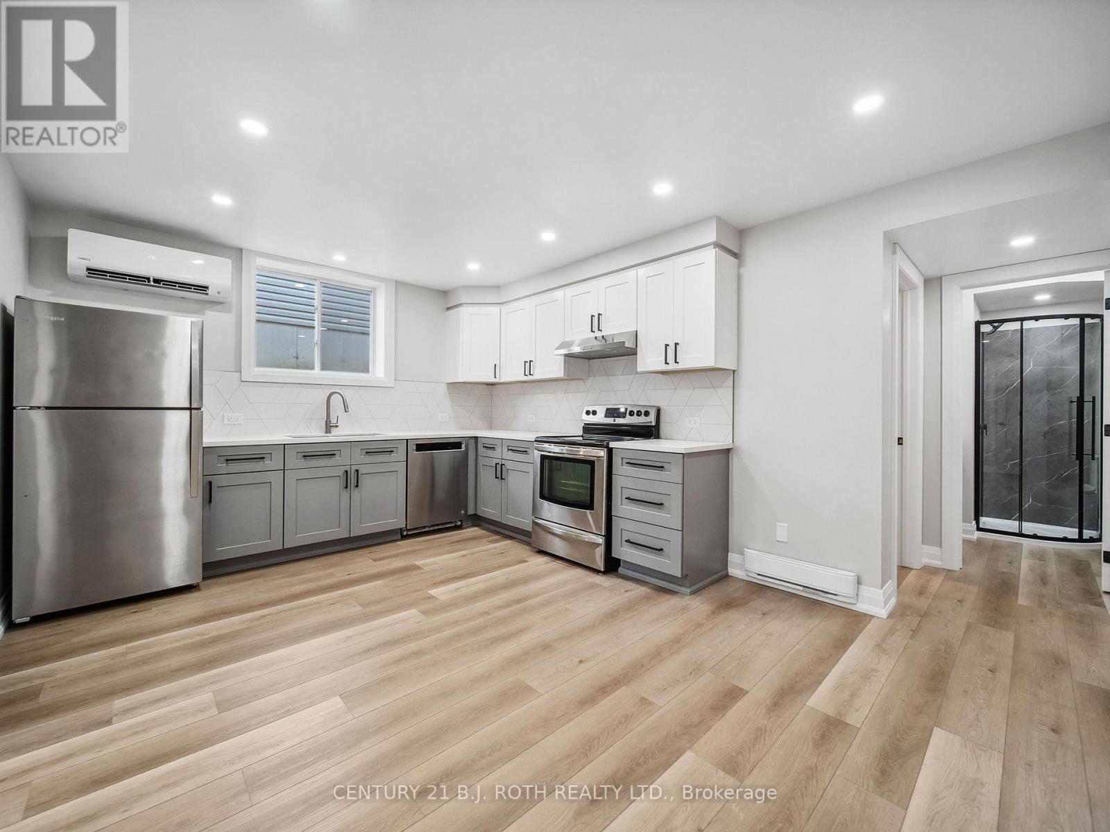 A modern kitchen with wooden floors and stainless steel appliances.
