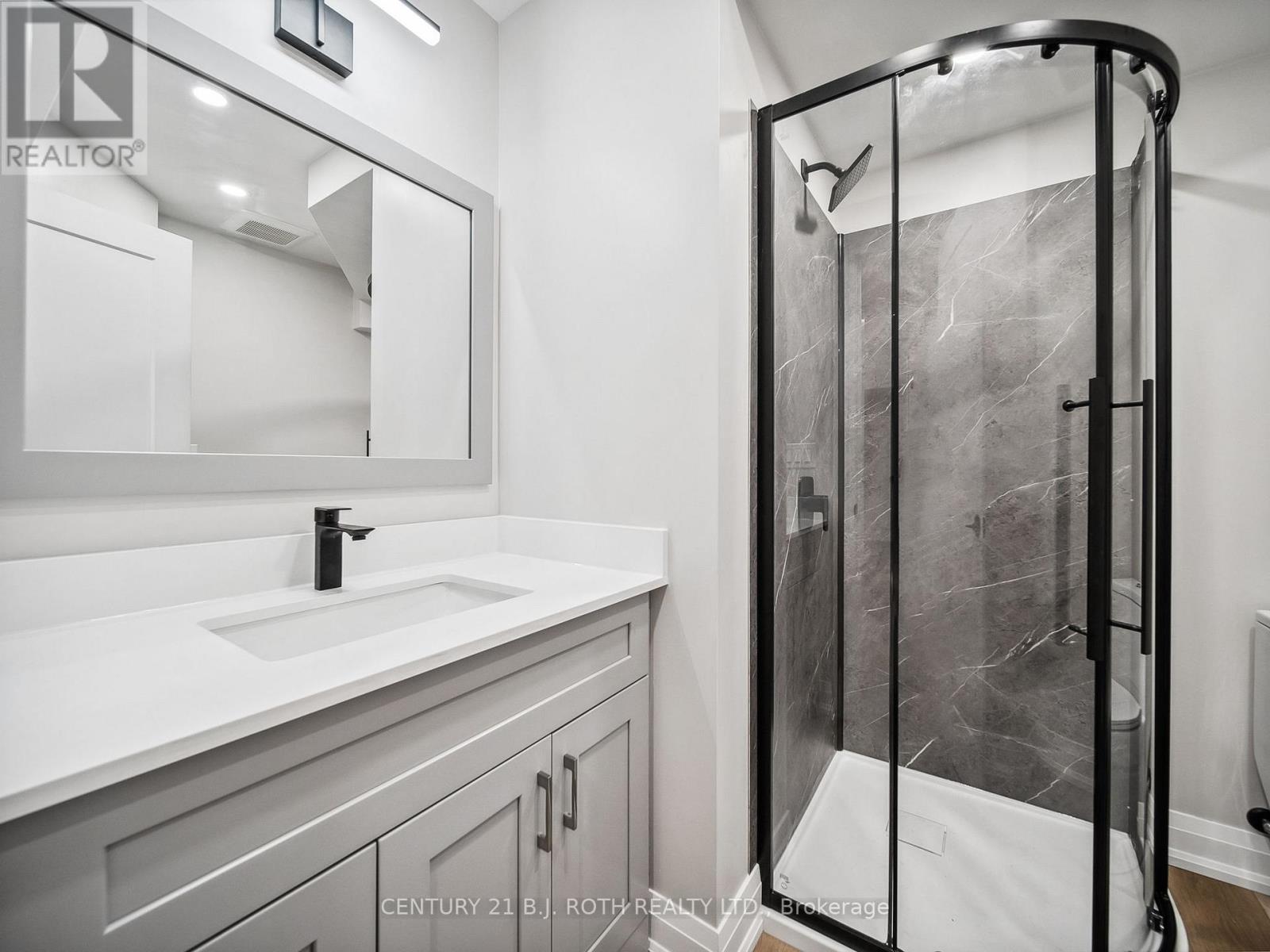 A bathroom with a sink, mirror, and shower.