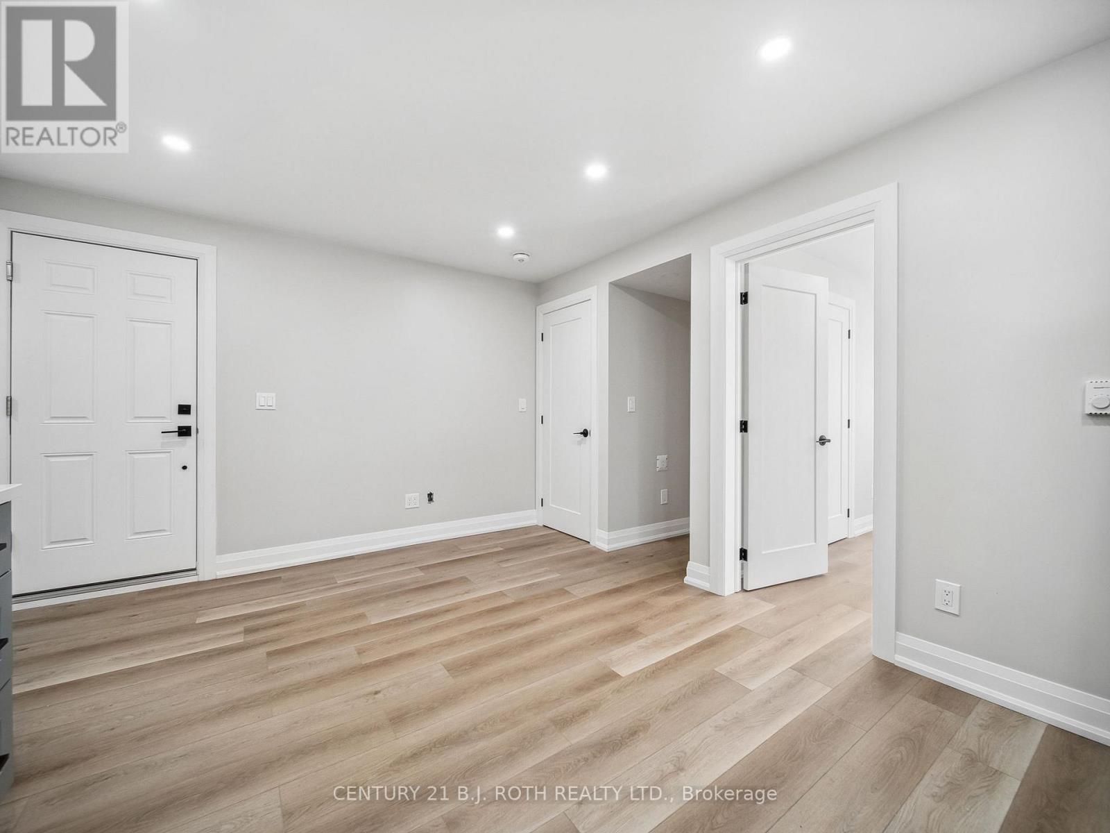 A spacious room with white doors and wooden flooring.