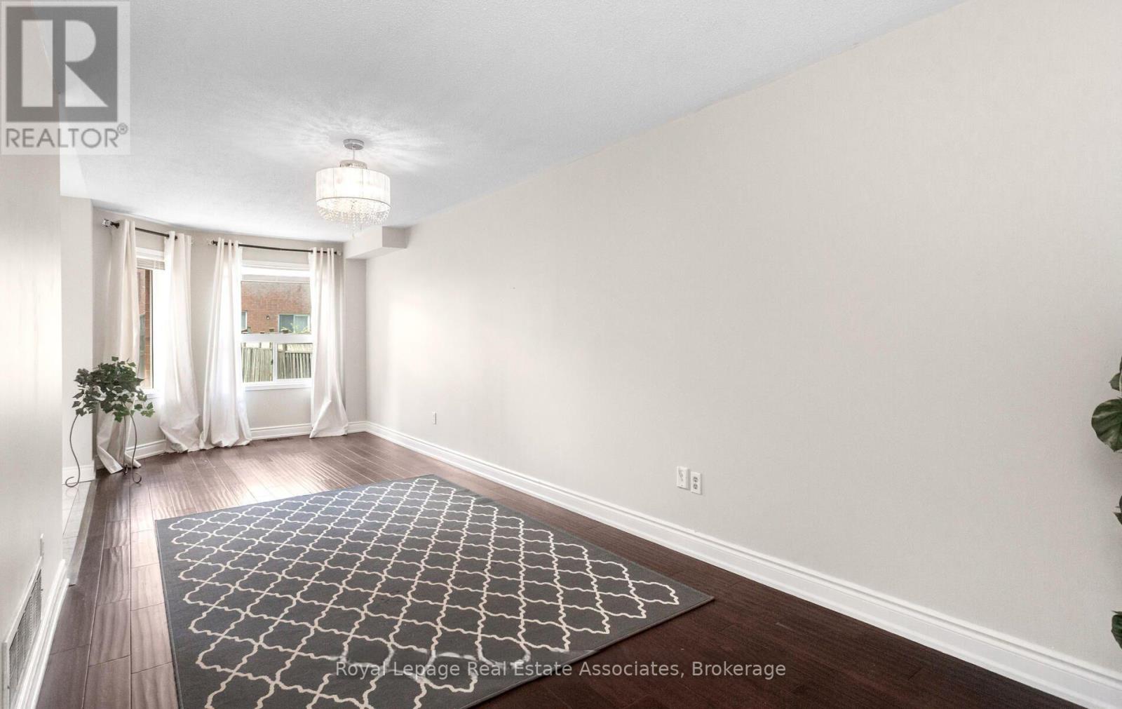 A room with a rug on the floor and a plant on the side table.