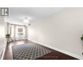 A room with a rug on the floor and a plant on the side table.