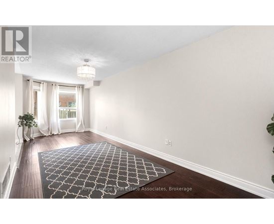 A room with a rug on the floor and a plant on the side table.