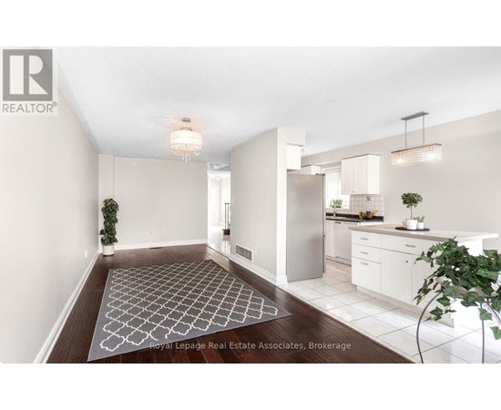 A well-lit, modern kitchen and dining area with a patterned rug on the floor.