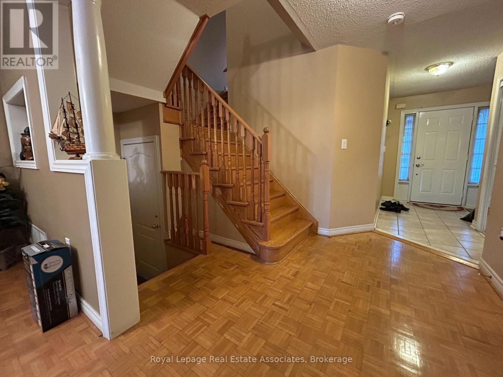A spacious room with a wooden staircase and a white door.