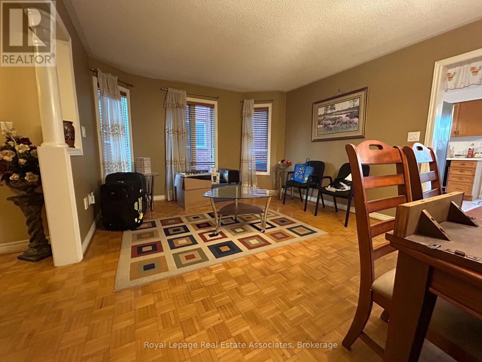 A living room with a rug on the floor and a painting on the wall.