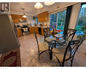 A kitchen with a table and chairs in the foreground and a view of a backyard through the window.