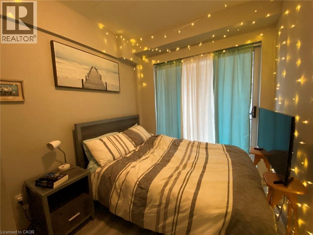 A bedroom with a bed, nightstand, and a painting on the wall.