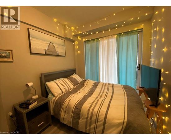 A bedroom with a bed, nightstand, and a painting on the wall.