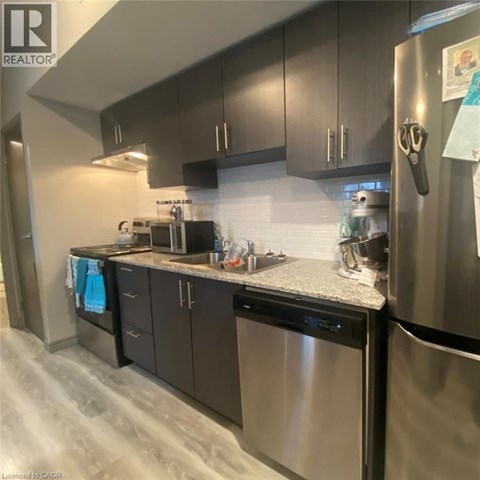 A kitchen with a refrigerator, microwave, and oven.