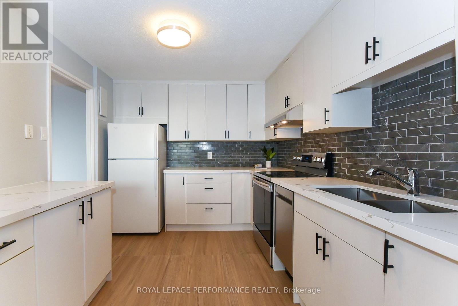 A kitchen with white cabinets and a brick wall backsplash.