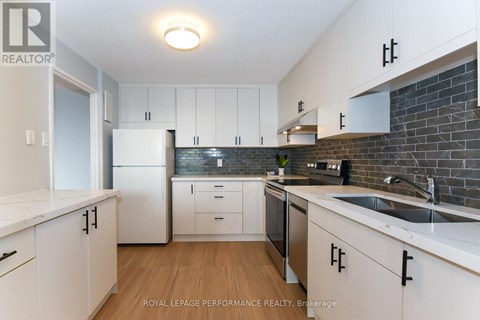 A kitchen with white cabinets and a brick wall backsplash.