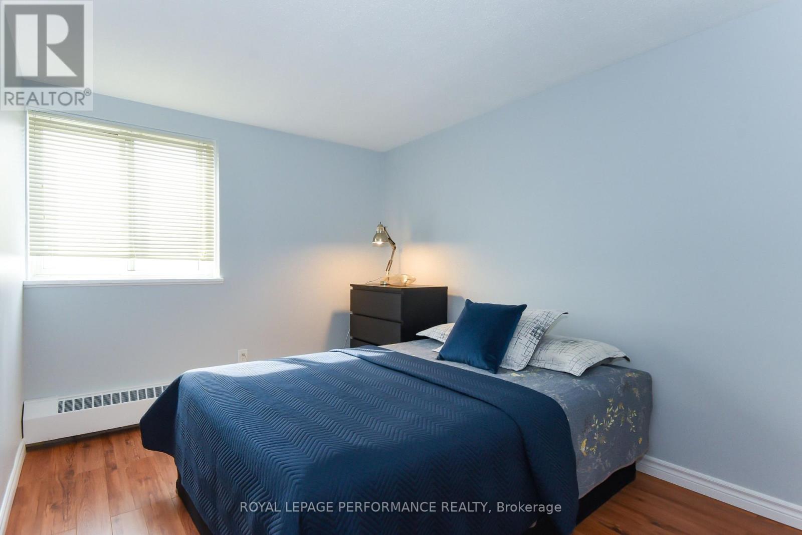 A bedroom with a bed, nightstand, and window.