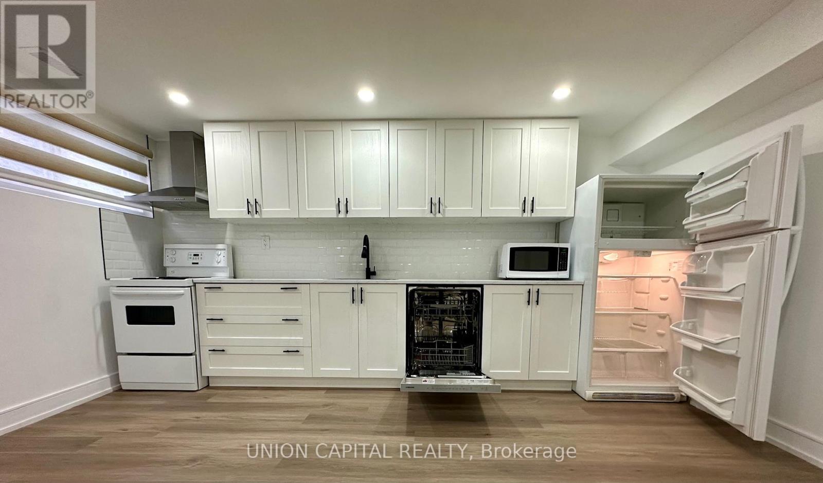 A kitchen with white cabinets and appliances is on the market with Union Capital Realty.