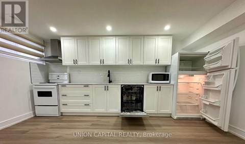 A kitchen with white cabinets and appliances is on the market with Union Capital Realty.