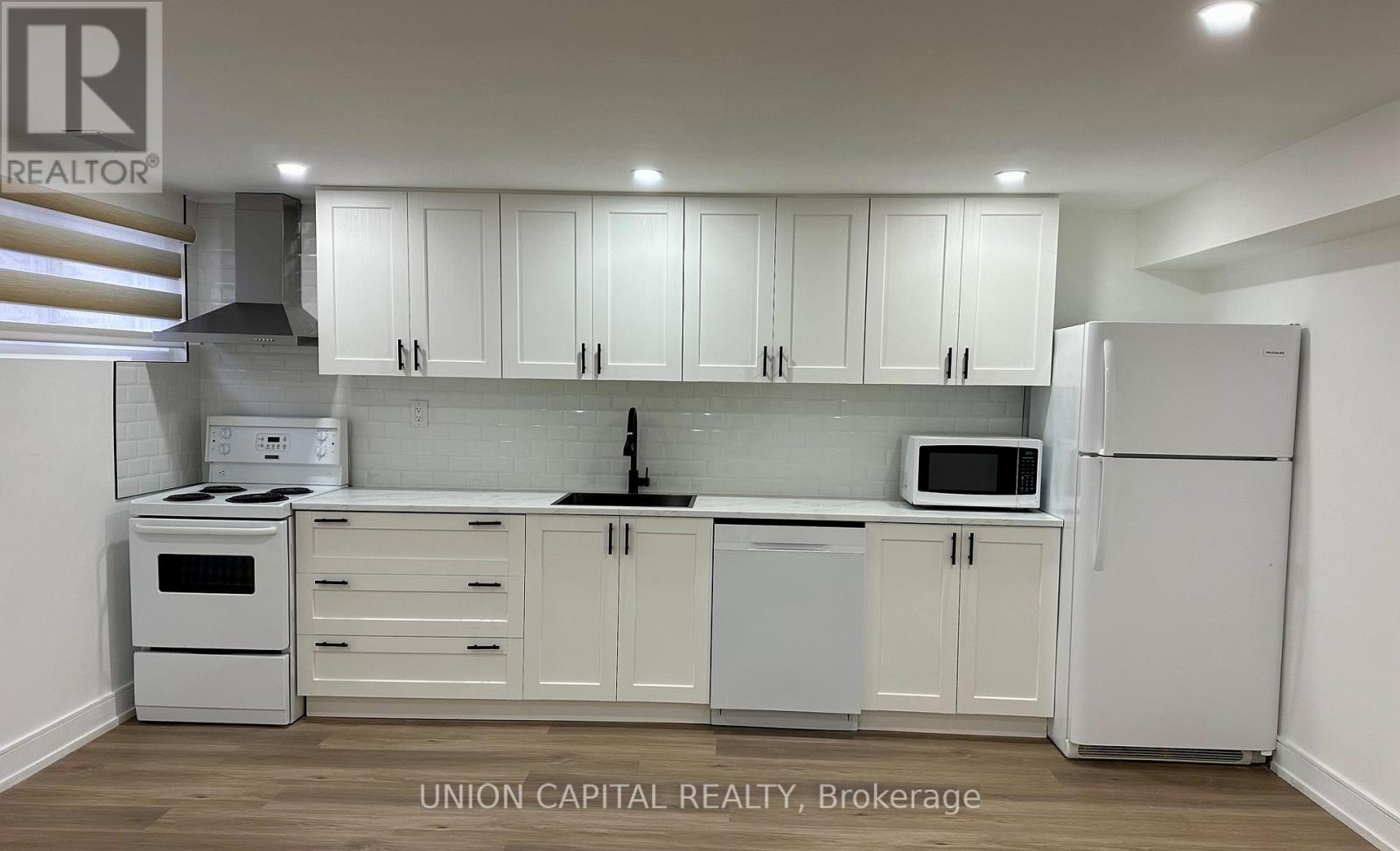 A kitchen with white cabinets and appliances.
