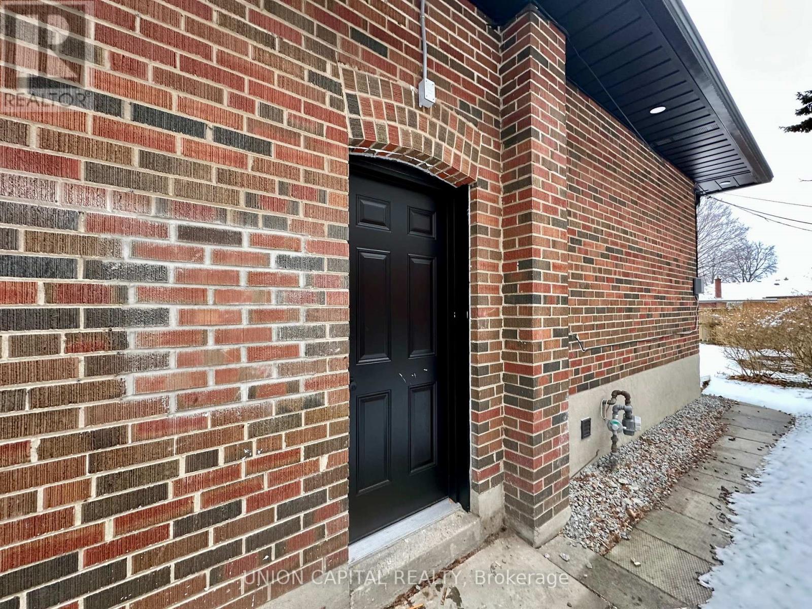 A brick building with a black door and a small window.