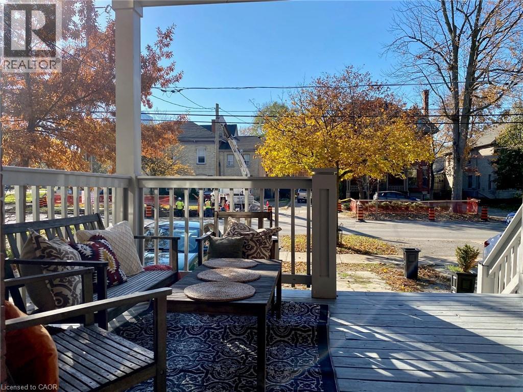 A wooden deck with a table and chairs is surrounded by trees with autumn leaves.