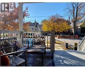 A wooden deck with a table and chairs is surrounded by trees with autumn leaves.