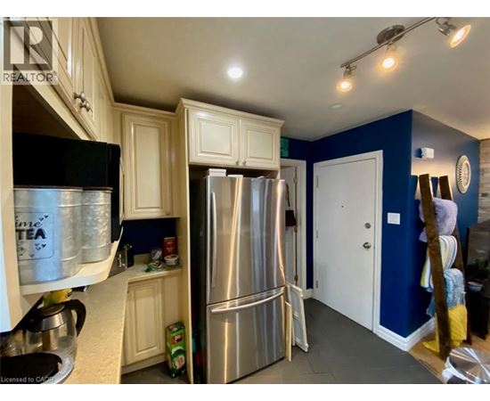 A kitchen with white cabinets and a black fridge.