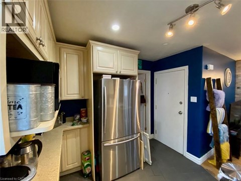 A kitchen with white cabinets and a black fridge.