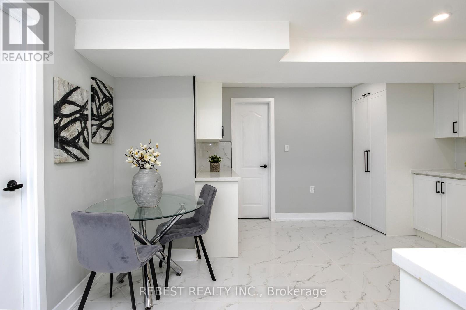 A modern dining room with a glass table and grey chairs.