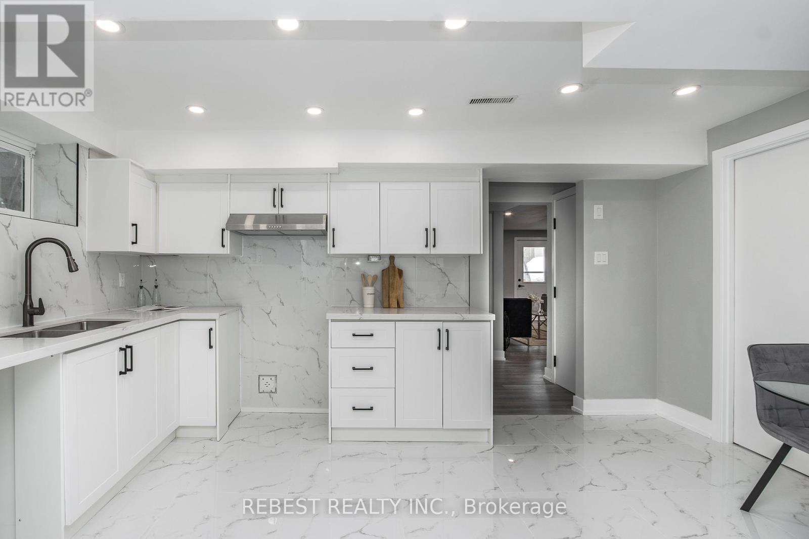 A modern kitchen with white cabinets and marble countertops.