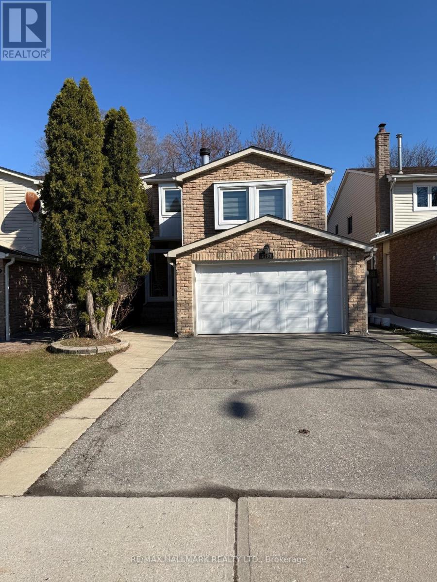 A house with a white garage door and a tree in front.