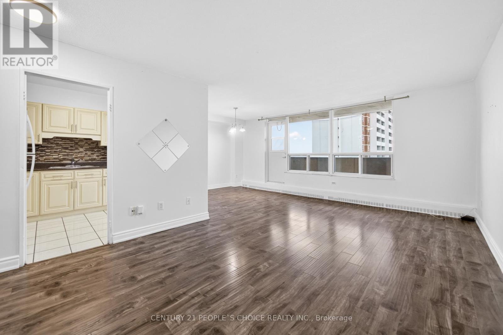 A spacious room with wooden flooring and a large window.