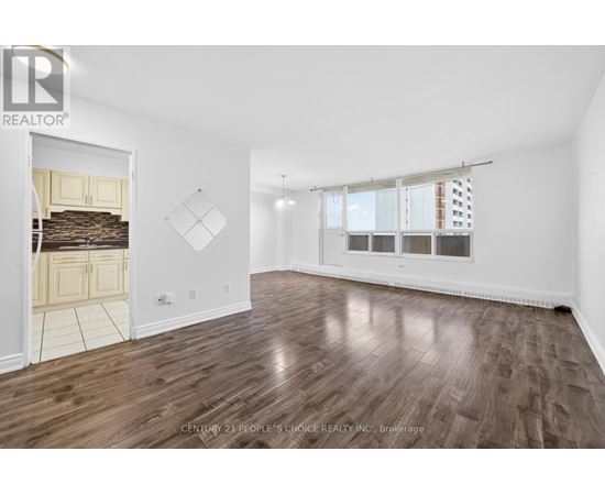 A spacious room with wooden flooring and a large window.