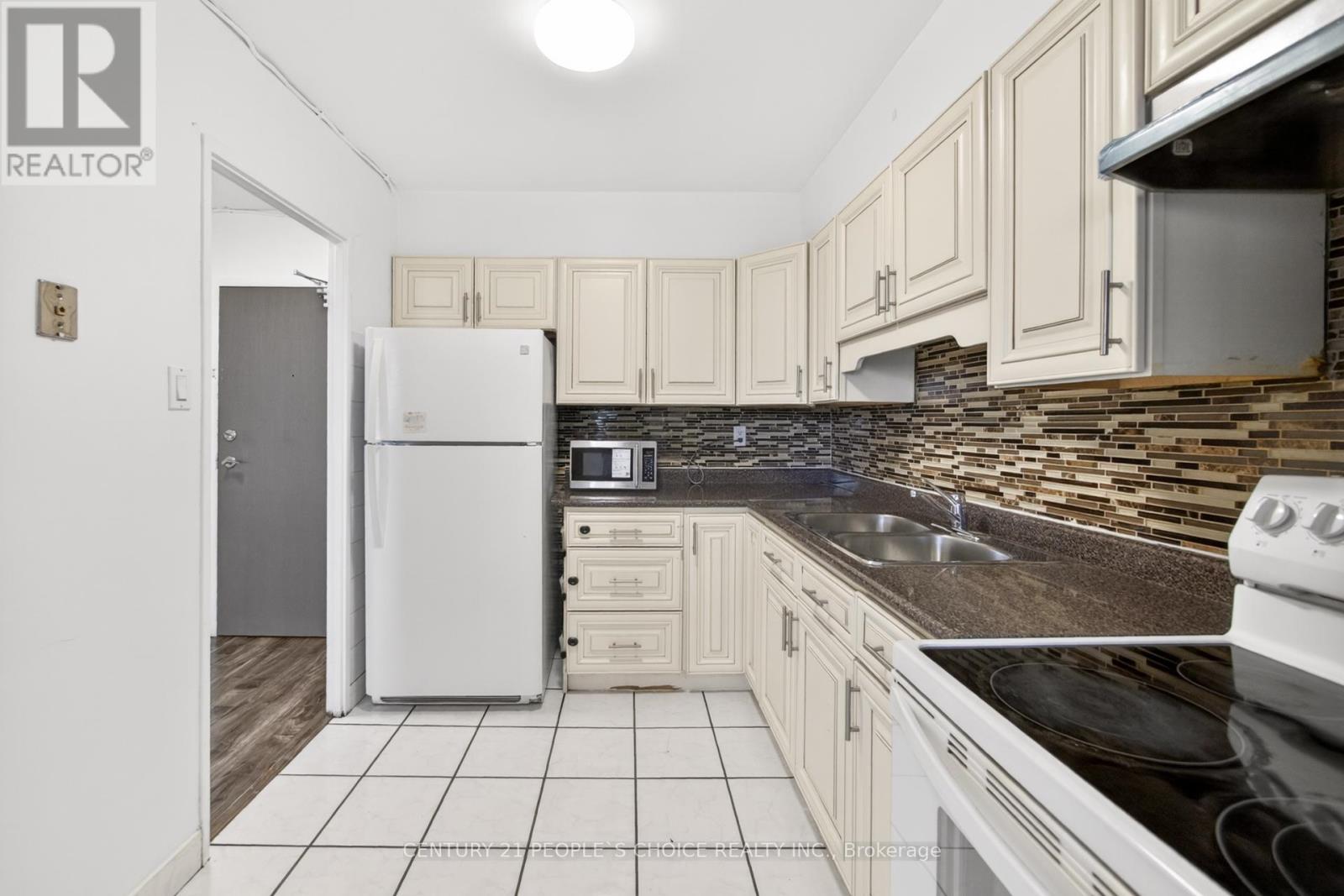 A kitchen with a white fridge and black countertops.