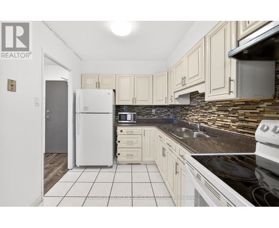 A kitchen with a white fridge and black countertops.