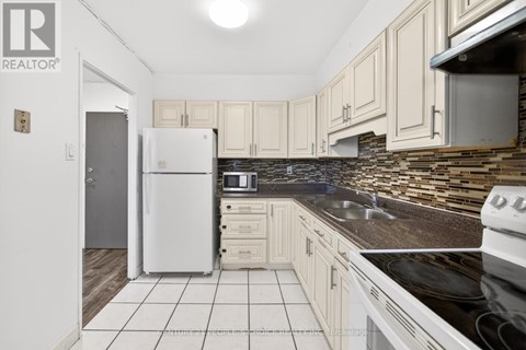 A kitchen with a white fridge and black countertops.