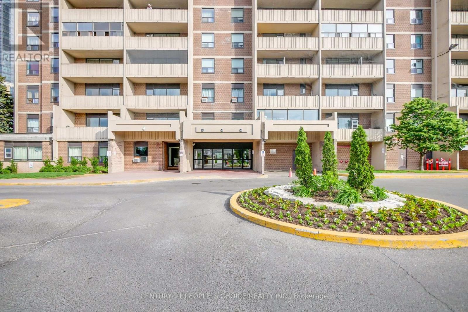 A large apartment building with a landscaped courtyard in front.