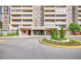 A large apartment building with a landscaped courtyard in front.