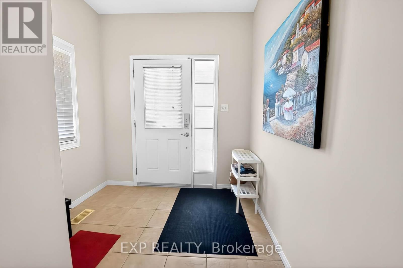 A room with a door, a window, and a painting on the wall.