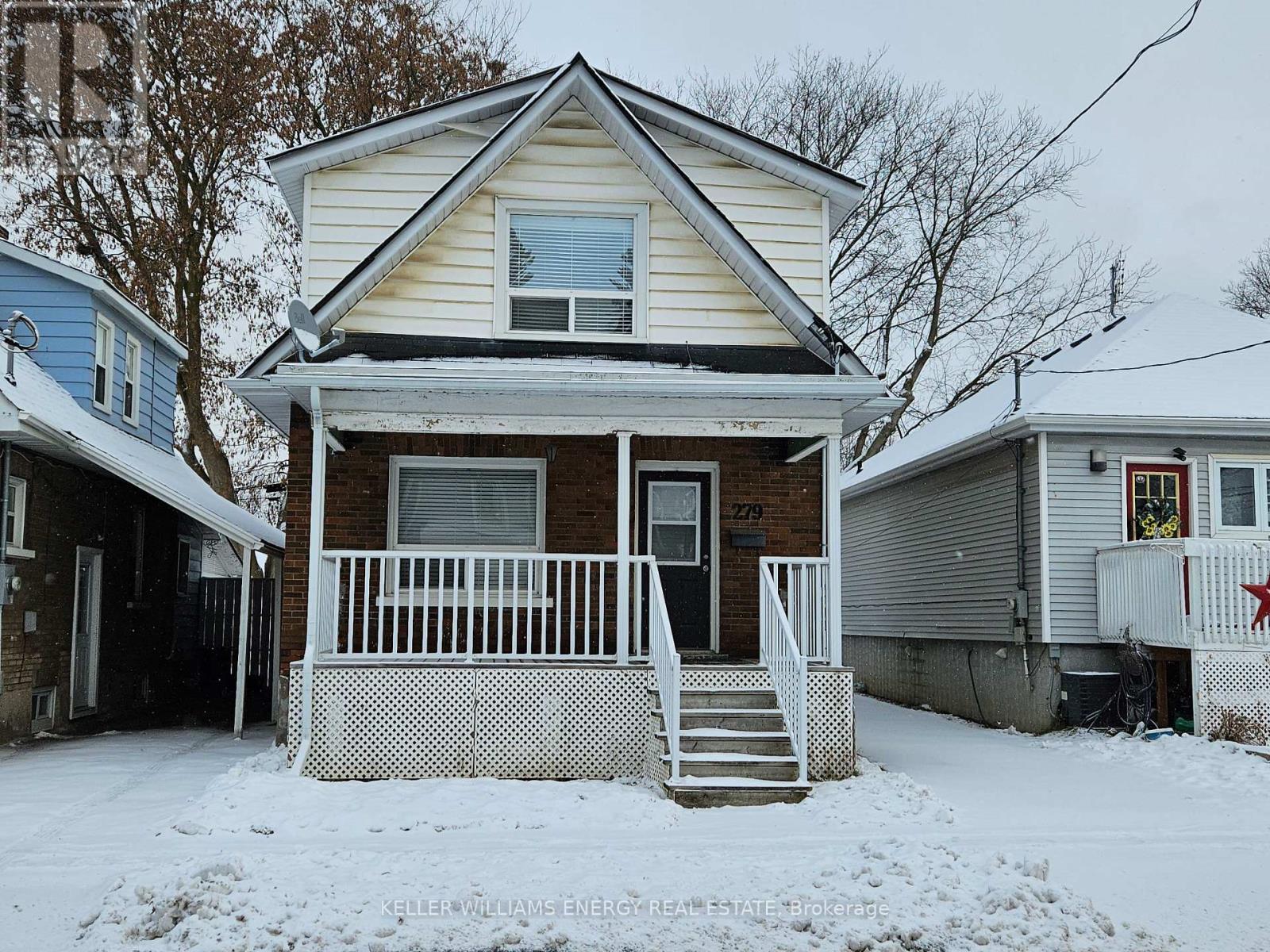 A house with a porch and a white fence in the snow.