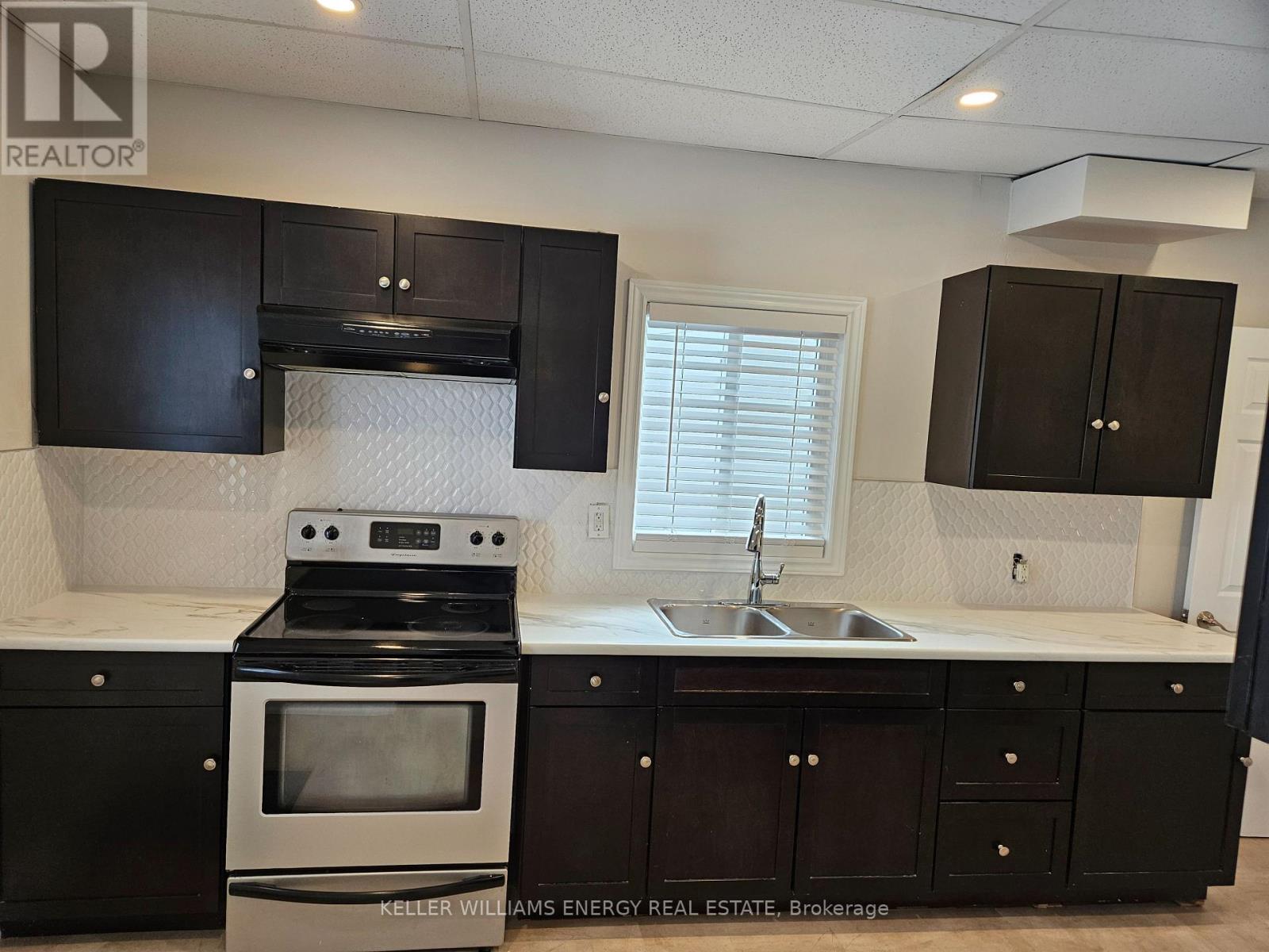 A kitchen with black cabinets and a stove top oven.